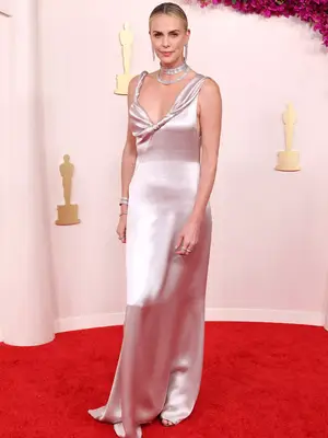 Charlize Theron wears a silver gown with twisted detail and silver jewelry to the 2024 Oscars