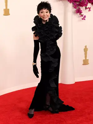 Rita Moreno wears a sculptural black gown and statement jewelry to the 2024 Oscars