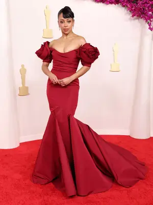 Liza Koshy wears a red gown with rose sleeves to the 2024 Oscars