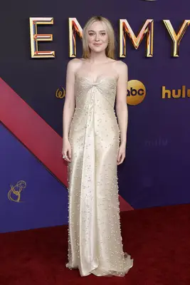 Dakota Fanning wears a champagne-colored strapless gown with pearl appliques to the 2024 Emmy Awards red carpet