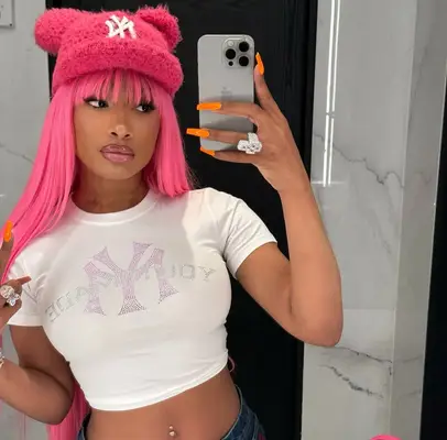 Megan Thee Stallion shows off her hot pink hair and orange nails in a mirror selfie.