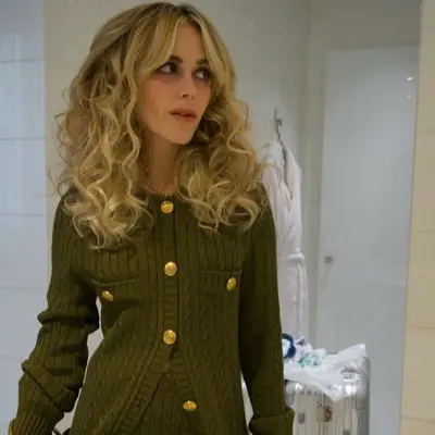 Kiernan Shipka at the Chloe fashion show in Paris with meg Ryan-coded rom come curls and a green sweater