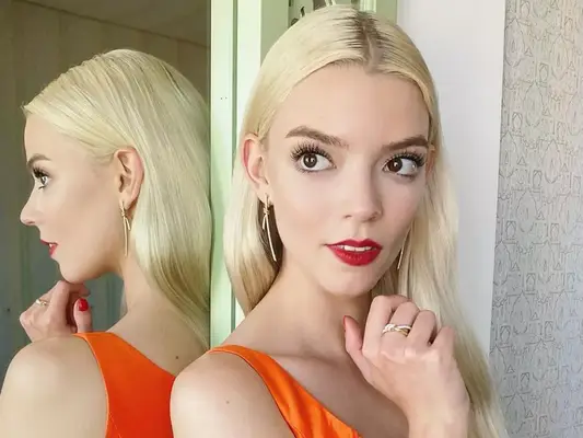 Anya Taylor joy in an orange dress, red lips, and simple jewelry