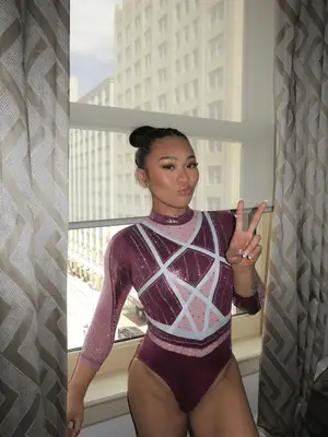 suni lee wearing purple and pink gymnastics leotard