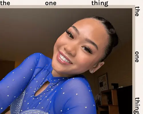 suni lee wearing makeup, slick bun, and blue leotard