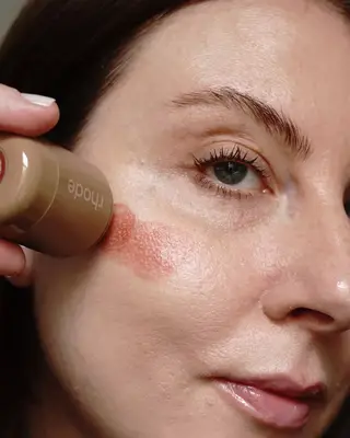 Woman applying Rhode blush on her cheek