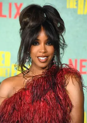 Kelly Rowland at an LA premiere in 2021 with a feathered one-shoulder dress and a feathered fringe and top knot 