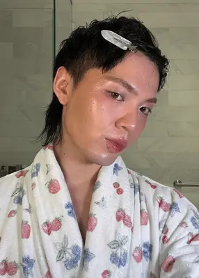 Person with glowing skin and a hair clip, wearing a robe with a floral pattern