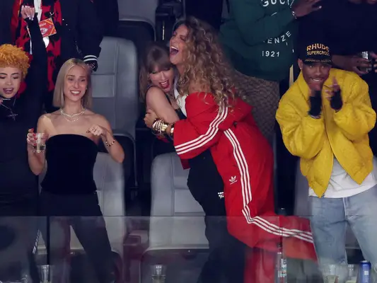 Blake lively hugging Taylor swift at the Super Bowl with big, voluminous curly hair