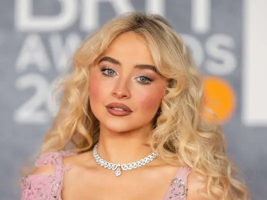 Sabrina Carpenter wearing glowy pink makeup on the red carpet.