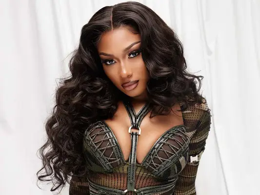 Megan Thee stallion with a wavy middle part hairstyle and camouflage top