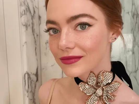 Emma stone wearing a low bun and large floral choker
