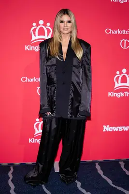 hiedi klum in black suit posing against red step and repeat 