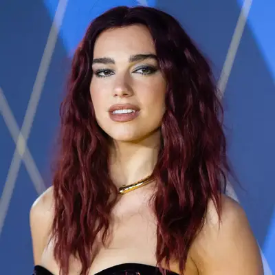 Dua Lipa at he Argylle red carpet with her red hair in indie sleaze waves while wearing a sequin red dress