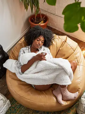 Woman sitting on beanbag while on her phone