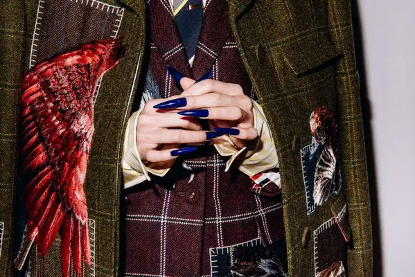 Long navy blue coffin nails on a model wearing multiple jackets