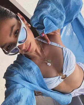Shay Mitchell selfie, wearing wrap around sungalsses and a blue and white bathing suit