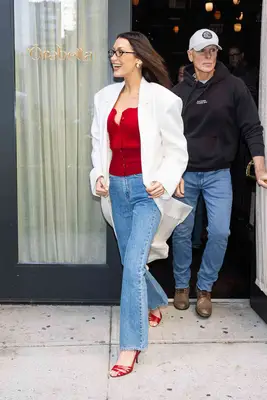 Bella Hadid leaving her Orabella pop-up wearing a red sweater and white coar