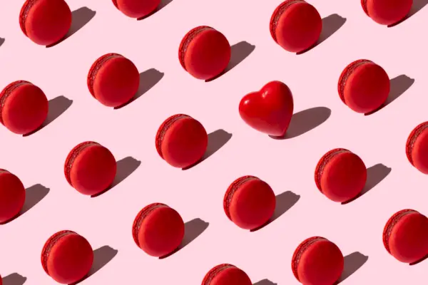Pattern made of tasty red color macaroons and heart.