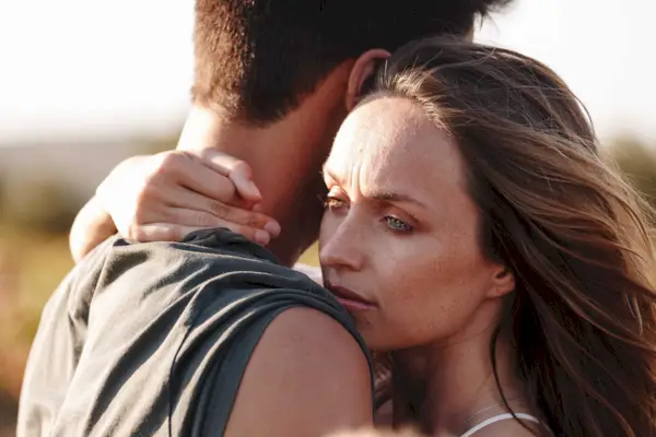 Couple hugging, woman looking worried
