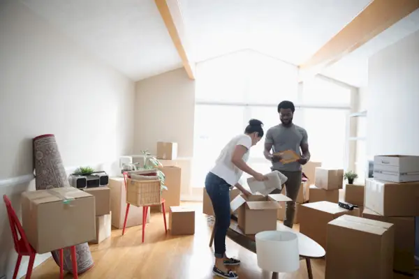 Young couple packing belongings in cardboard boxes, moving house