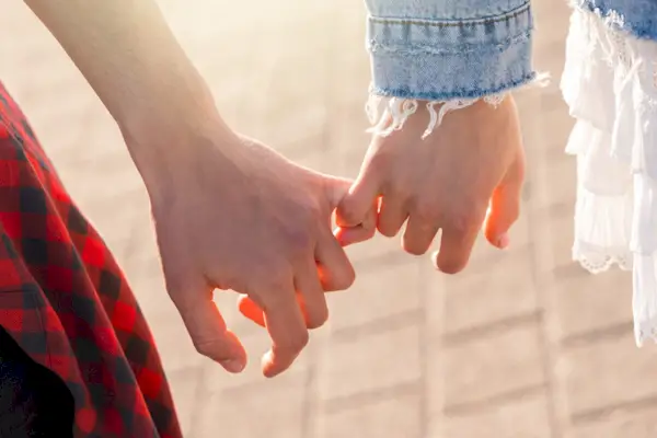 pár se drží za ruce s malíčkem sevření