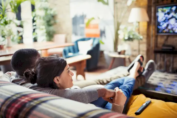 Milující mladý pár sledování televize na pohovce v obývacím pokoji