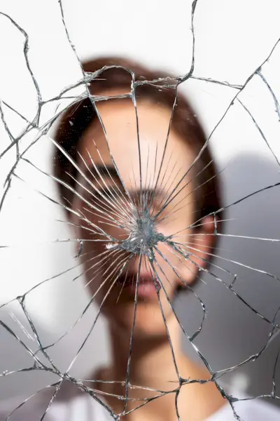 uma mulher olhando para um espelho de vidro quebrado