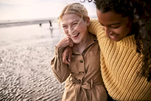 Two happy female friends embracing on the beach