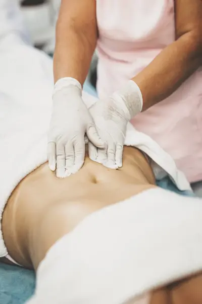 Female massage therapist treating customer with abdomen massage