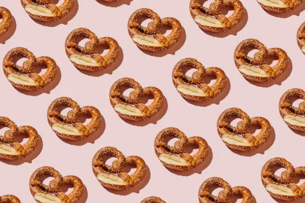 Creative layout with bread pretzels. Pattern of bakery products handmade on pink background. Modern minimal food photography collage in pop-art style. Flat lay, top view