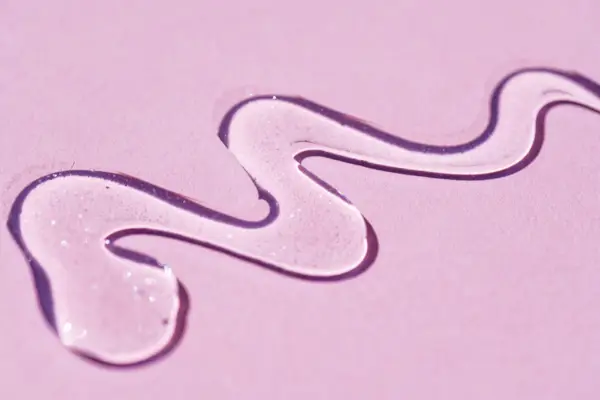 A portion of gel with sequins close-up texture on a pink background.