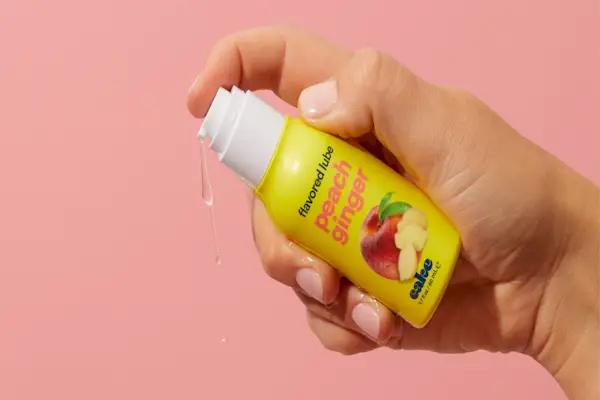 Hand holding a small bottle of flavored peach ginger lube
