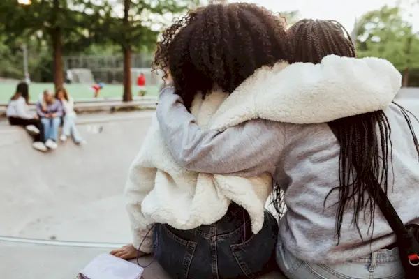 Rear view of female friends with arms around at skateboard park