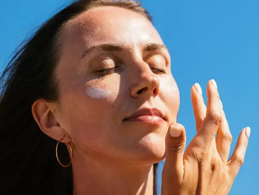 woman applying sunscreen to cheeks