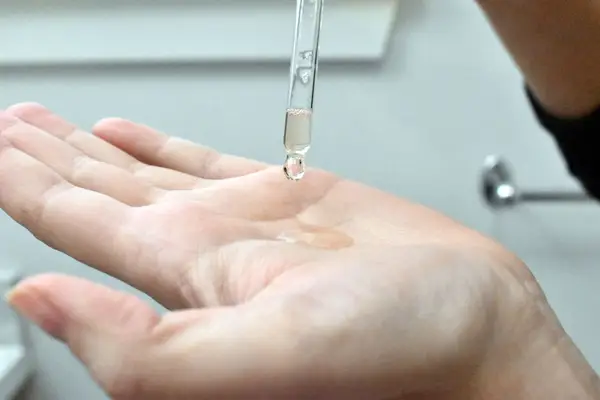 Dropper dispensing The Ordinary Lactic Acid 10% + HA onto hand palm