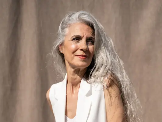 woman with silver hair posing against gray backdrop