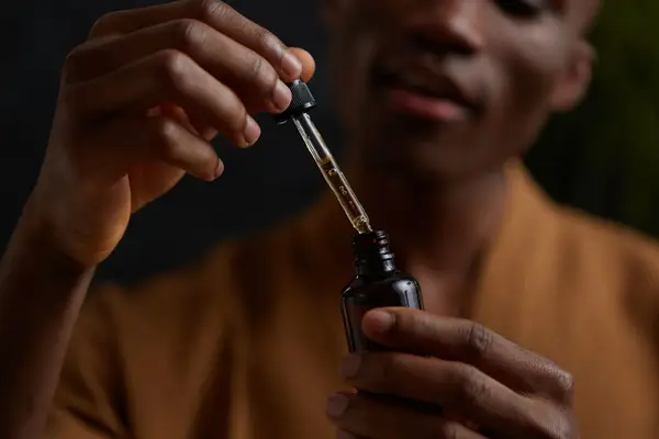 man holding vial of tea tree oil