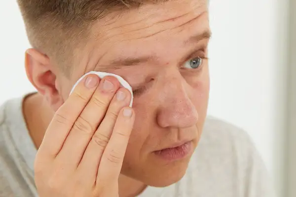 Person using Tata Harper Nourishing Makeup Removing Oil Cleanser on a cotton pad on their closed eyelid 