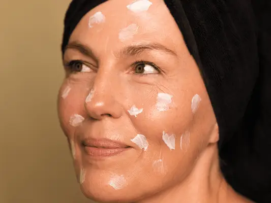 Older woman with skincare cream on face