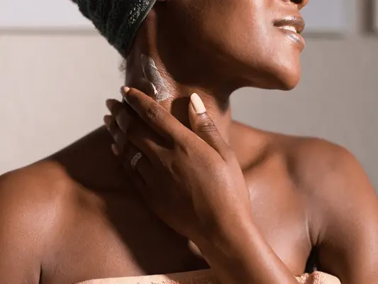 black woman applying cream on neck 