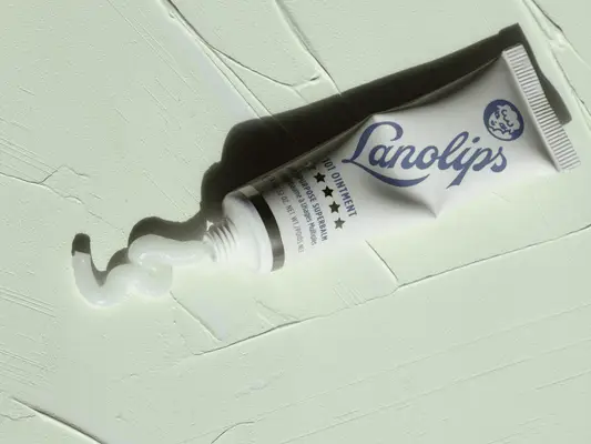 Lanolips tube bottle on a mint green background.