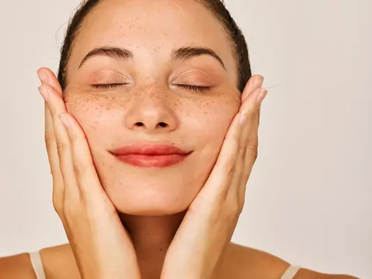 A person with closed eyes and hands on their cheeks in a relaxed pose