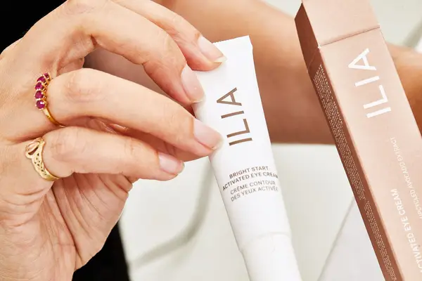 Hand holding a tube of ILIA Bright Start Retinol Alternative Brightening Eye Cream.