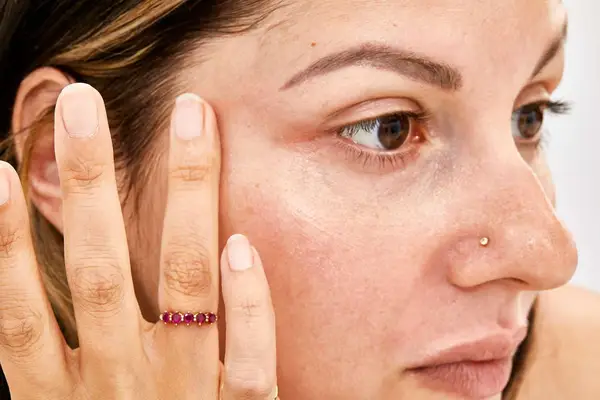 Closeup of a person applying ILIA Bright Start Retinol Alternative Brightening Eye Cream under their eye.
