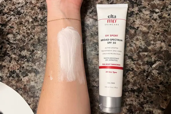 Arm covered with EltaMD UV Sport Broad-Spectrum SPF 50 Sunscreen next to the tube 