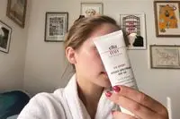 Hand holding a tube of EltaMD UV Sport Broad-Spectrum SPF 50 Sunscreen in front of face