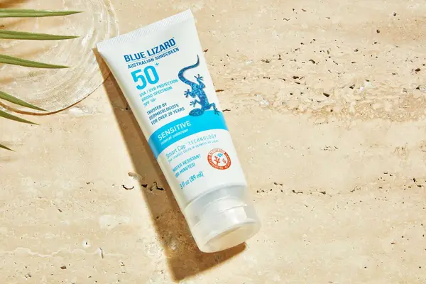 Hand dispensing Isdin Eryfotona Actinica Mineral SPF 50+ Sunscreen onto other hand with nearby tray and marble countertop