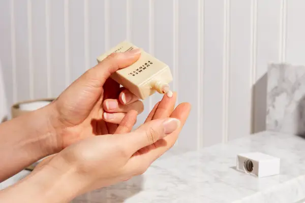 Hand dispensing Summer Fridays ShadeDrops Broad Spectrum SPF 30 Mineral Milk Sunscreen onto fingertip