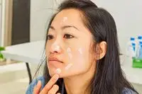 Hand dotting sunscreen onto face